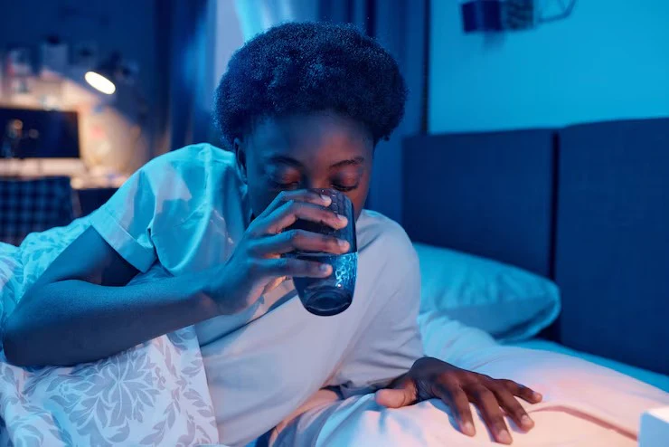 A person drinking water in bed